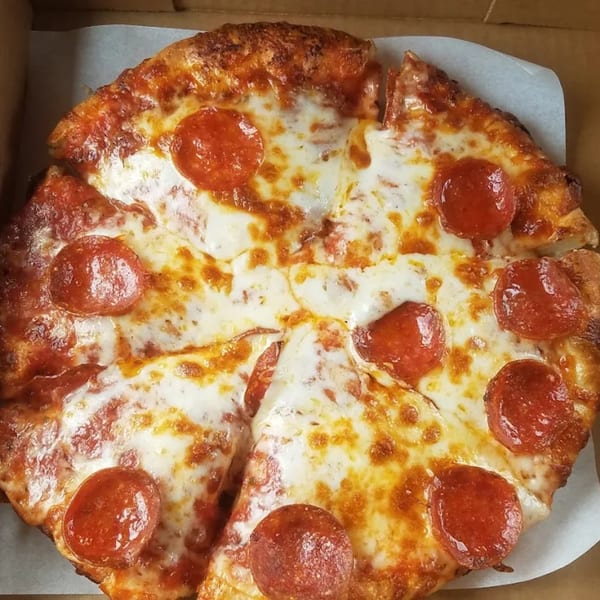 A whole pepperoni pizza, cut into slices, with melted cheese and crispy crust in a box.
