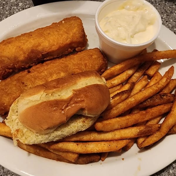 A plate of fried fish, french fries, a bun, and a side of tartar sauce.