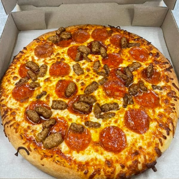 A whole pepperoni and sausage pizza in a cardboard box, with melted cheese and a golden crust.